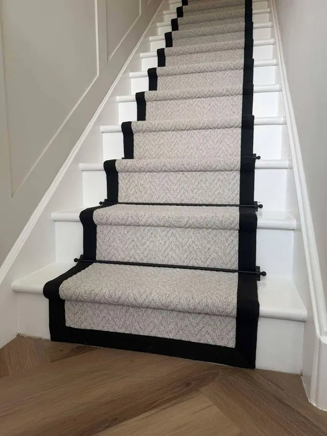 A bordered runner on white stairs