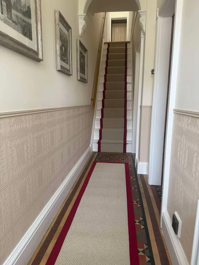 A red-bordered runner through the hall and stairs