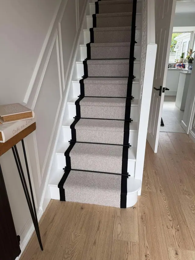 A pale runner with dark binding on white stairs